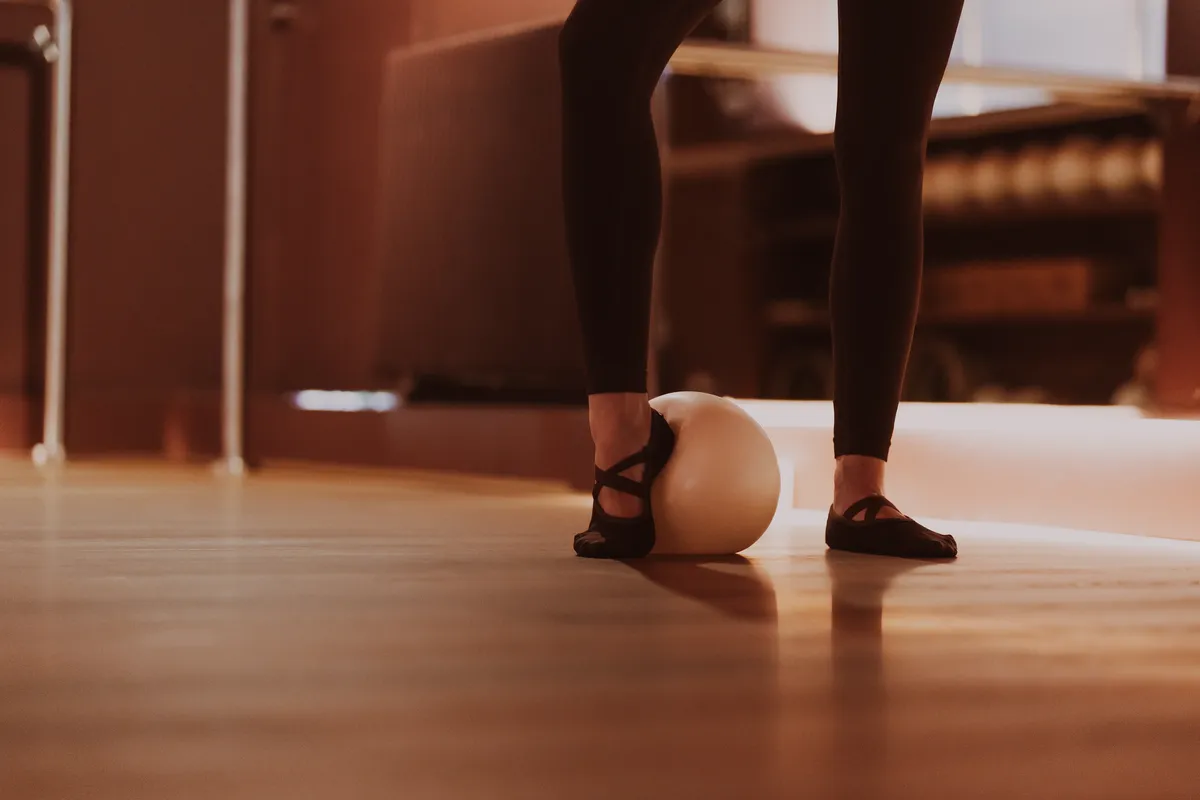 Pieds en chaussons antidérapants encadrant un ballon de Pilates sur le parquet
