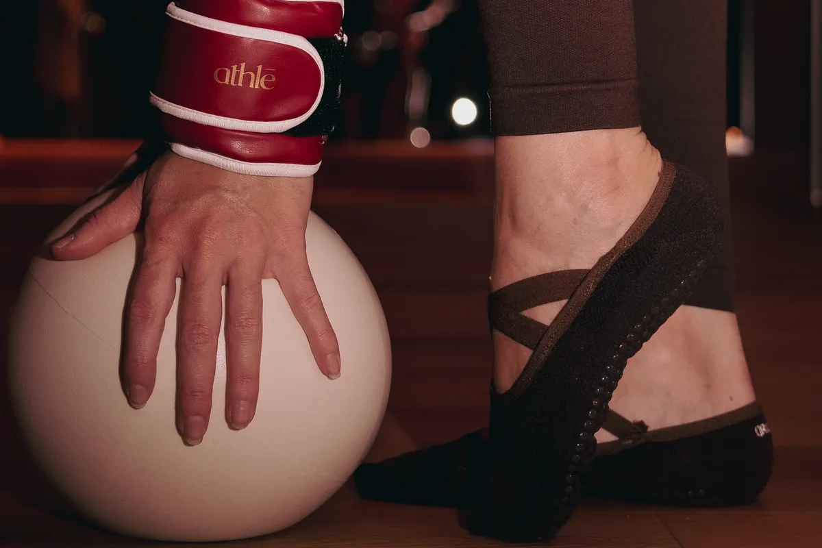Main lestée d’un poids de poignet posée sur un ballon de Pilates