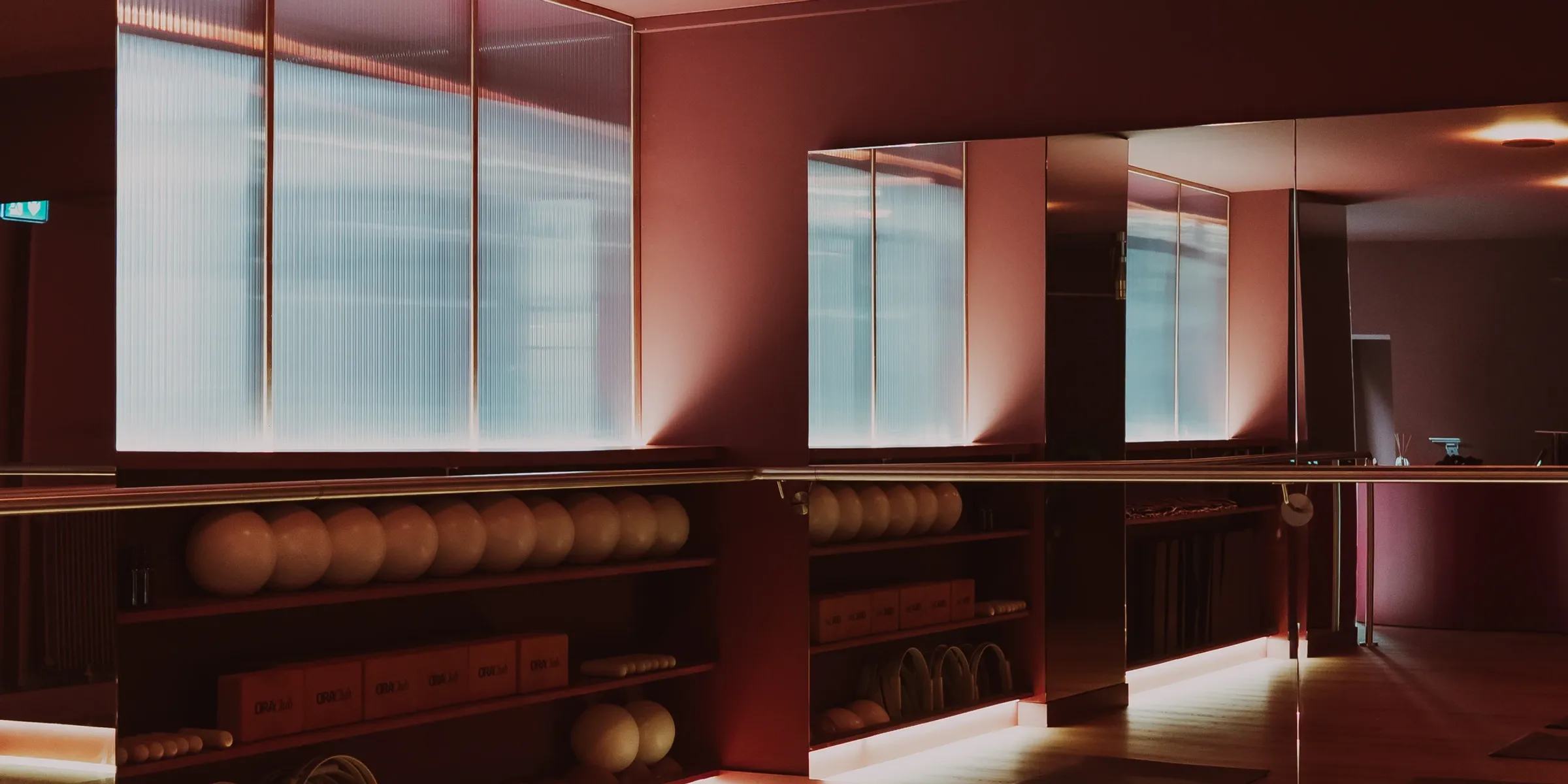 Salle principale du studio Ora Club : verrière cannelée, miroirs et matériel rangé